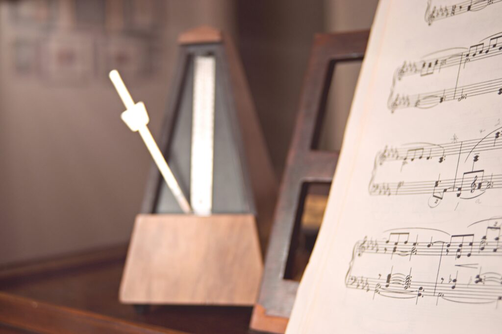 un métronome et une partition pour illustrer la régularité nécessaire à l'apprentissage de la musique